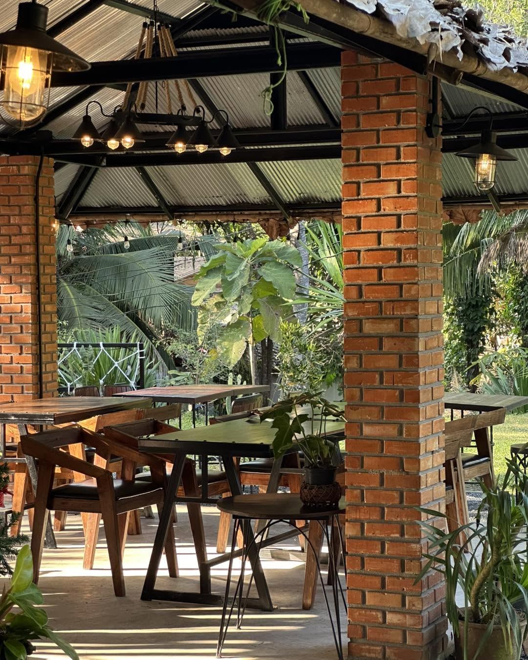 ศาลาเสาอิฐ โต๊ะไม้ โคมไฟวินเทจ ท่ามกลางสวนเขียว ร้านริมธารา แม่ริม